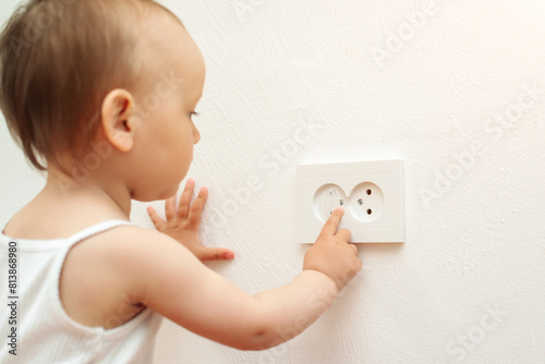 Baby touching the power socket. Baby and child safety concept. Curious little boy playing with electric plug.