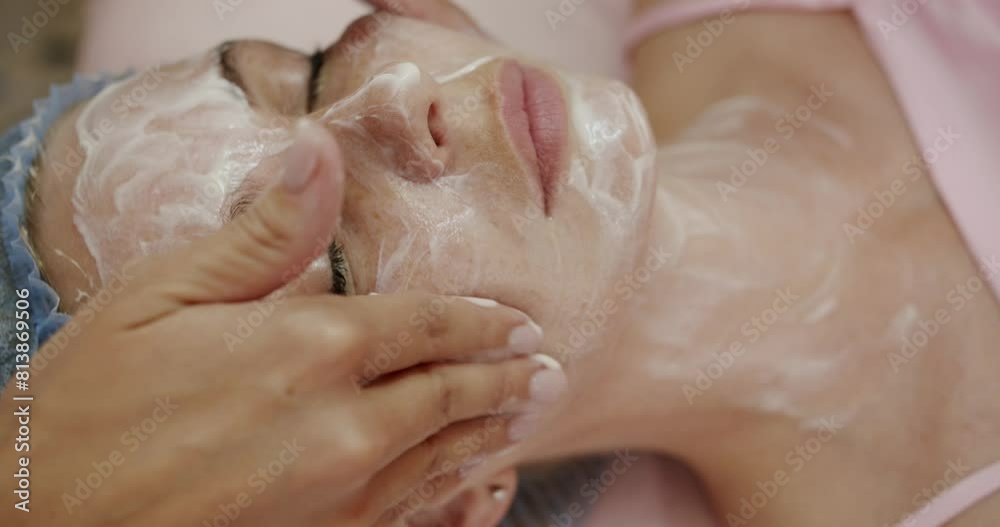 A beautician carefully applies a nourishing facial mask to a woman face, providing a luxurious skin care treatment in a soothing spa environment. Professional Beautician Applies Nourishing Facial Mask A beautician carefully applies a nourishing facial mask to a woman face, providing a luxurious skin care treatment in a soothing spa environment. Professional Beautician Applies Nourishing Facial Mask