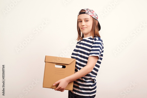 Young smiling boy holding the box on white background. Child with carton package. Delivery Concept.