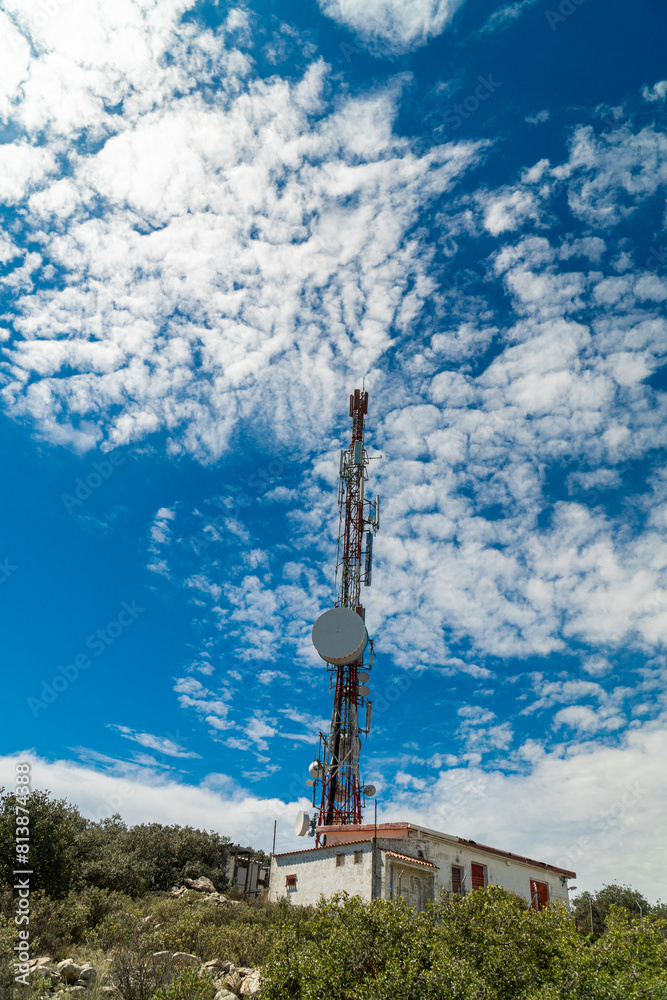 Obraz premium Communications tower on a mountain, signal repeater, sunny morning day.