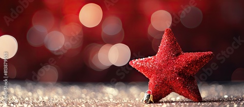 A small red star Christmas decoration is seen on a glitter background providing the perfect New Year decor. Copy space image. Place for adding text and design