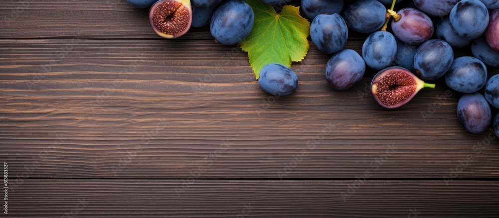 Top view of ripe blue plums and figs creating a beautiful autumn harvest fruits background on a wooden surface with copy space Top view of ripe blue plums and figs creating a beautiful autumn harvest fruits background on a wooden surface with copy space