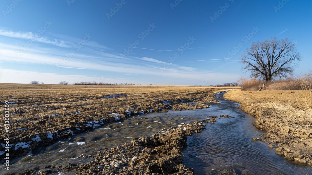 barren deserted field next to a flowing creek