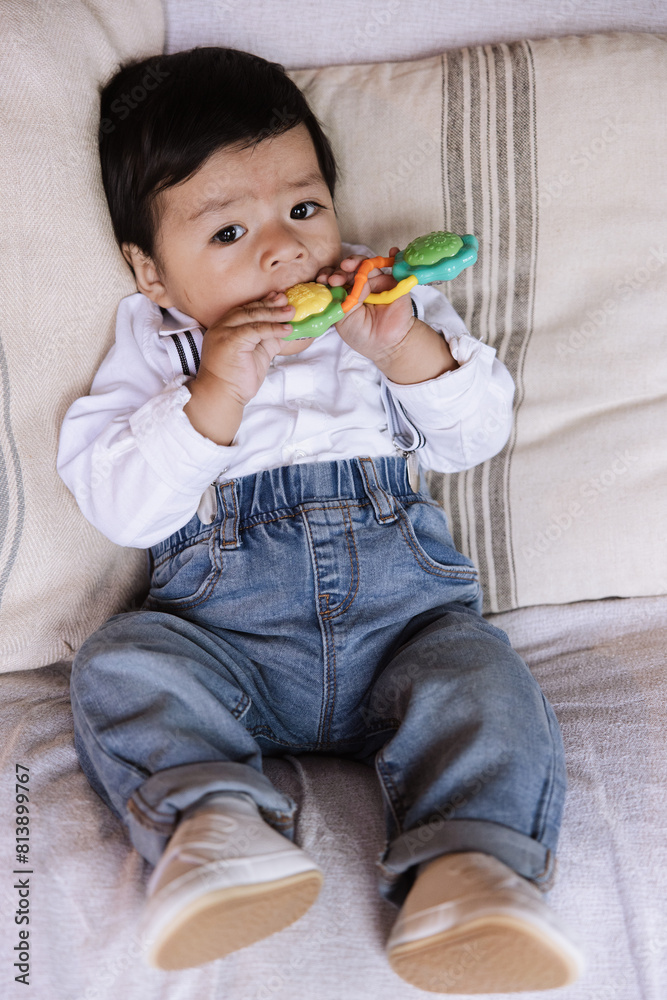 Relaxed baby boy teething on colorful toy. Relaxed baby boy teething on colorful toy.