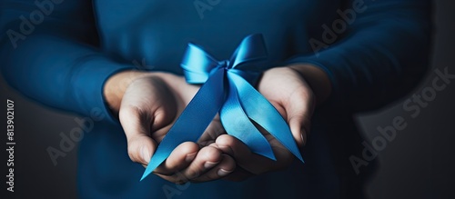 A middle aged person holds a blue ribbon in their hand symbolizing support care and charity for prostate cancer awareness The closeup image portrays the concept of medicine and oncology urging help f photo