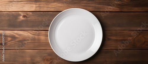 Top view of a white plate mockup placed on a dark wooden table background providing ample copy space for images