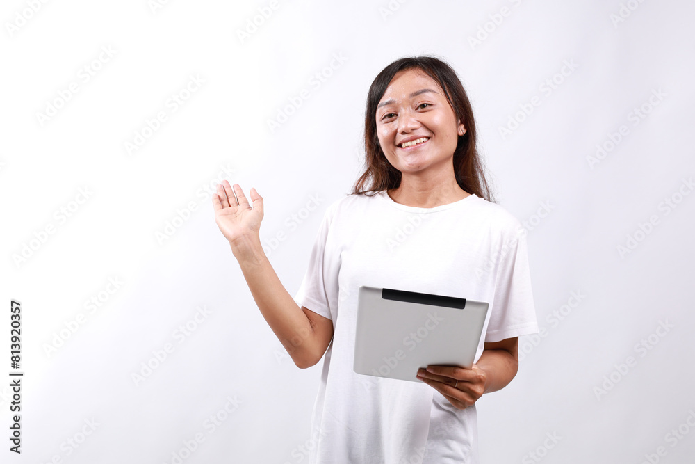 Attractive young asian woman holding a digital tablet while standing over white background presenting sideways Attractive young asian woman holding a digital tablet while standing over white background presenting sideways