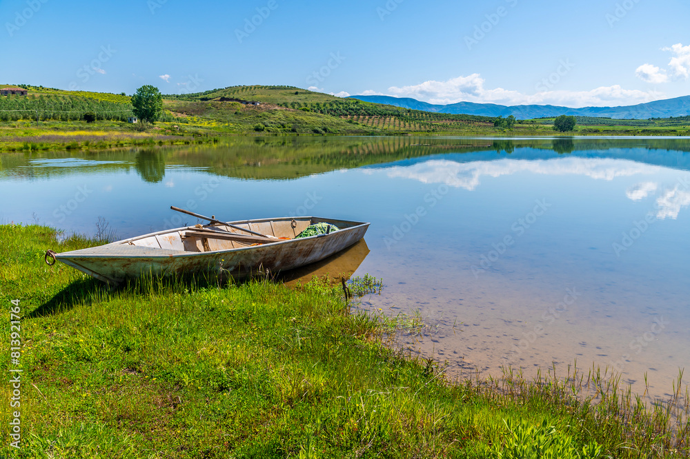 A view past a boat out across a lake at Belsh lakes in Albasan county, Albania in summertime