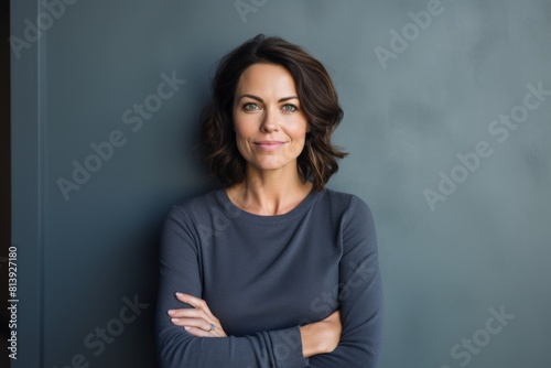 Portrait of a grinning woman in her 40s with arms crossed isolated in modern minimalist interior