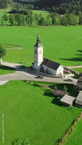 Traditional Slovenian Church of St. Andrei in Ravenska Kocna valley with the Kamnik-Savinja Alps in the background. An aerial summer view of the idyllic Alpine landscape in Zgornje Jezersko, Slovenia photo