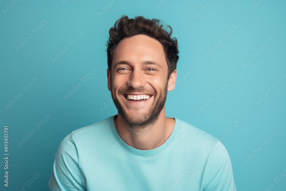 Portrait of a blissful man in his 30s smiling at the camera while standing against pastel blue background