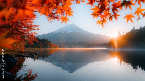 Mt. Fuji reflects in a serene lake framed by fiery red autumn leaves at sunrise, creating a tranquil and picturesque scene.