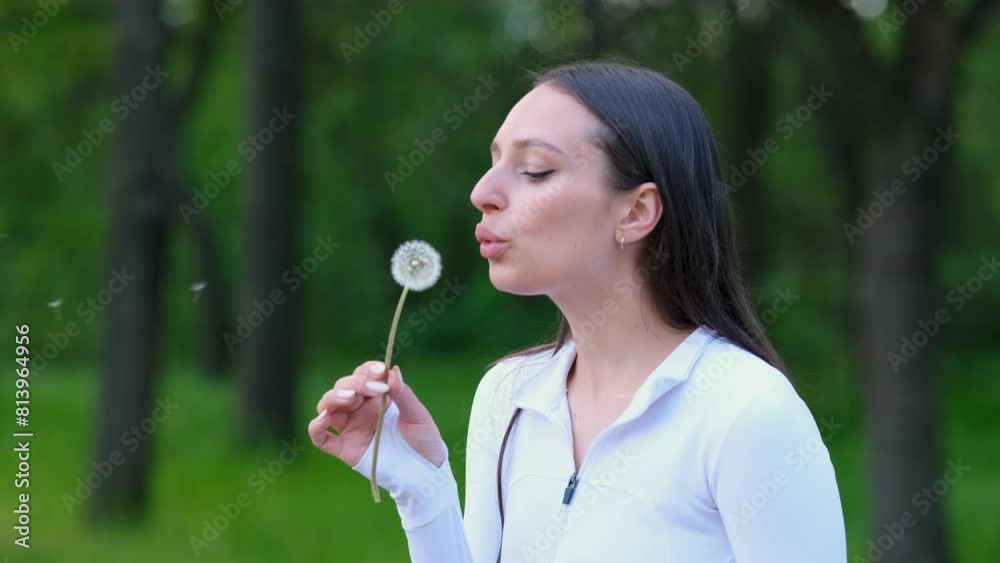A girl blows on a dandelion in the park, slow motion.