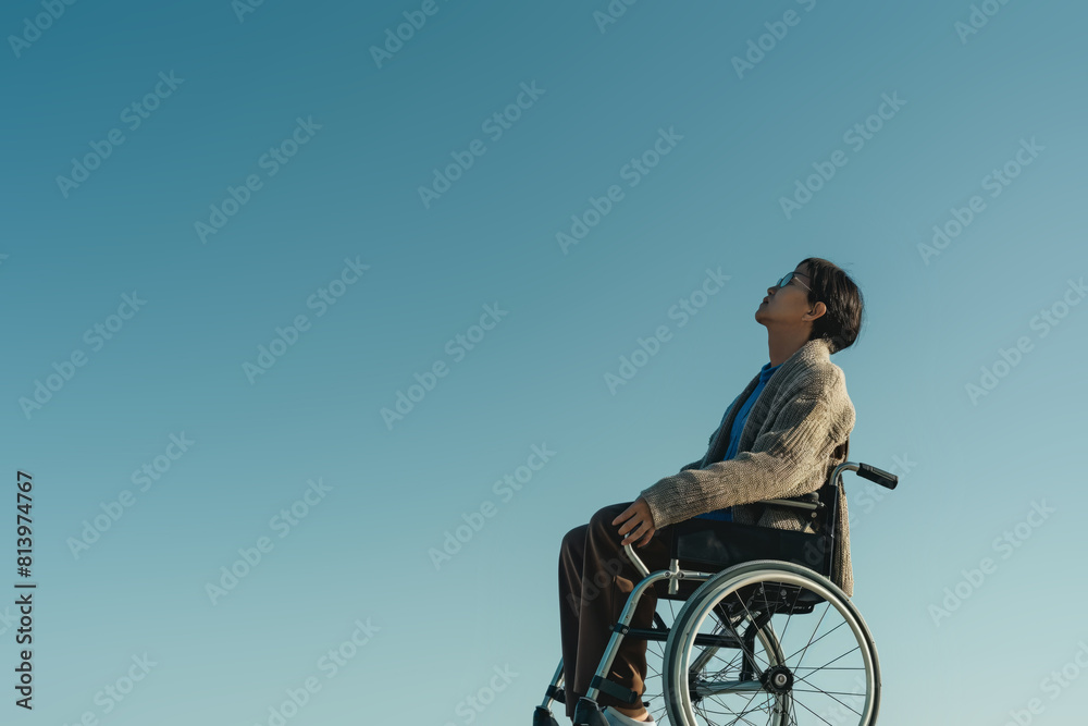 Disabled person in wheelchair against blue sky Disabled person in wheelchair against blue sky