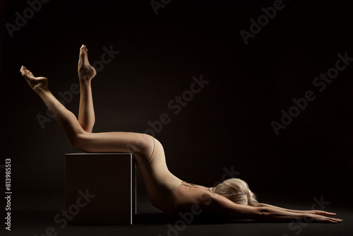 Sexy Woman Body Silhouette over Black. Sensual Female stretching lying down on Cube. Beautiful Fit Girl Body Side view doing Yoga Exercise