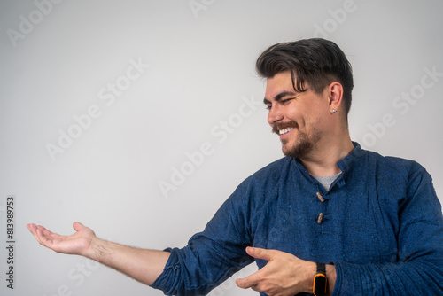 Young handsome man with beard over isolated background pointing to the side to present a product. Look over there! Portrait of cheerful excited joyful satisfied handsome man pointing on copy space
