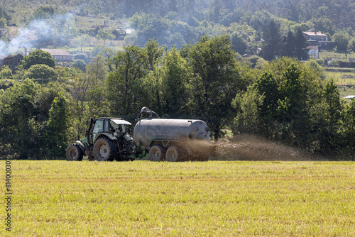 Scene of a tractor in a crop field spreading liquid manure