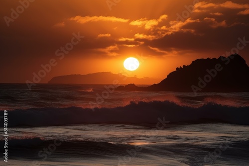Serene sunset view over the ocean with silhouetted rocks and rolling waves under a fiery sky