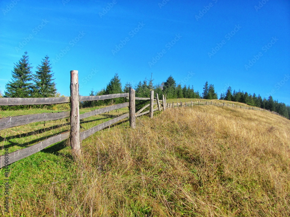 Obraz premium Rustic Wooden Fence on Hillside Meadow