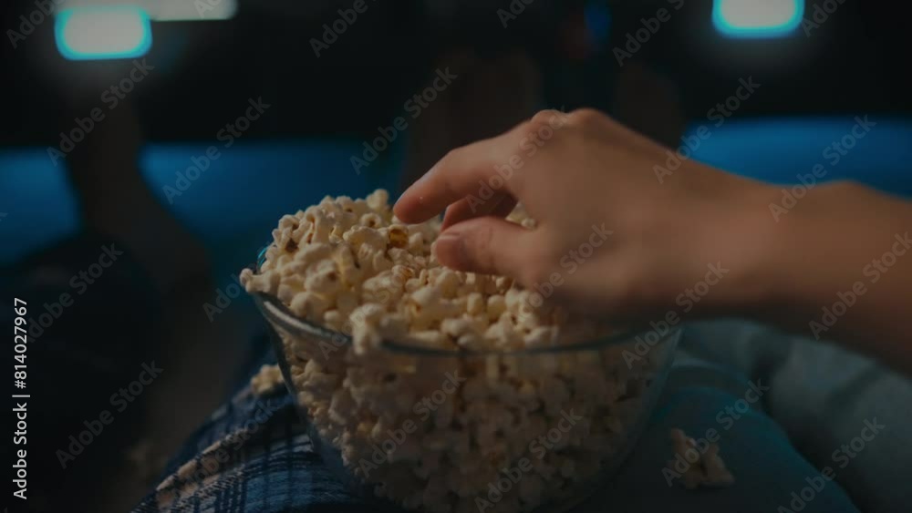 An evening movie session at home with a huge bowl of flavored popcorn in the hands of a young family. Husband, wife in front of the screen, enjoying these moments together
