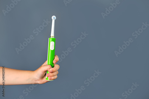 Child's hand holding an electric toothbrush