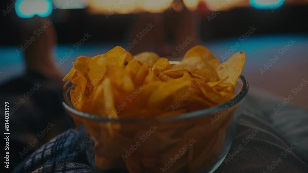 In the evening, in their home cinema, a young couple enjoys spending time together, cozying up on the sofa, snacking on chips and watching exciting episodes of their favorite TV series