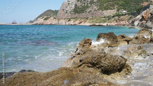 Sea waves crashing onto rocks on a summer day. Ship on the horizon.