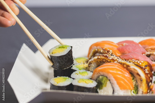 Tasty Colorful assorted Set of different type Sushi with chopsticks. Dinner in Japanese style. Healthy food. Filadelfia and Maki sushi rolls with Avocado, Tuna, Salmon, fish and Prawns.