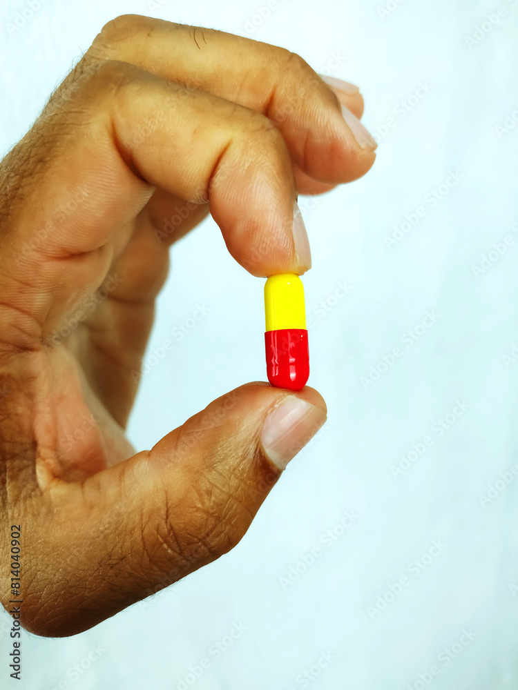 Black male hand holding a colorfull pill isolated on a white background
Black male hand holding a colorfull pill isolated on a white background