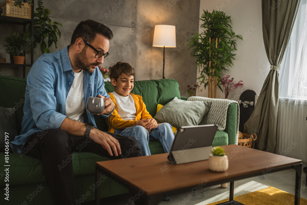 Father and son watch movie or cartoon on tablet at home Father and son watch movie or cartoon on tablet at home