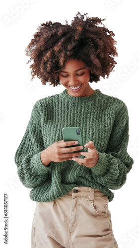 Portrait of a joyful young black woman in a green sweater, smiling as she interacts with her smartphone, isolated on a transparent background