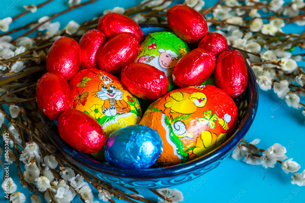 Obraz premium Multi-colored chocolate eggs in a blue bowl, seasoned for the feast of Easter