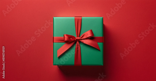 green gift box with a bow on a red background. Decoration for Christmas