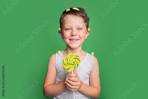 Smiling boy with lollipop on green background photo