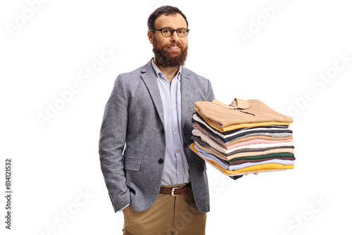 Bearded man holding folded clothes and smiling at camera