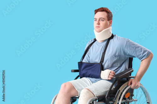 Injured young man after accident in wheelchair on blue background