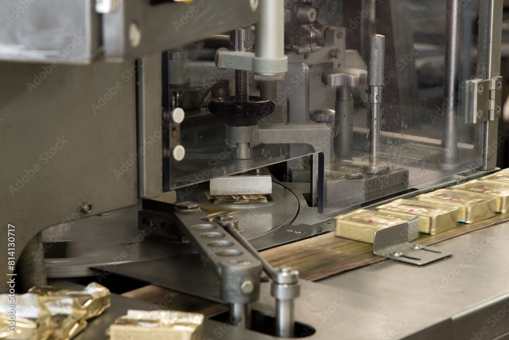 Factory producing cheese and butter in individual portion packaging on conveyor line. Equipment at dairy plant. Selective focus complete filling line Factory producing cheese and butter in individual portion packaging on conveyor line. Equipment at dairy plant. Selective focus complete filling line