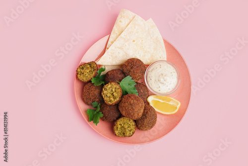 Plate with delicious falafel balls, pita and sauce on pink background photo