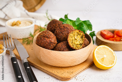 Wooden bowl with delicious falafel balls and lemon on light background, closeup