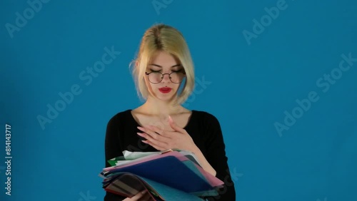 Woman office employee holds folders with documentation on blue background. Female licks finger to turn sheet. Concept of bad habit slow motion