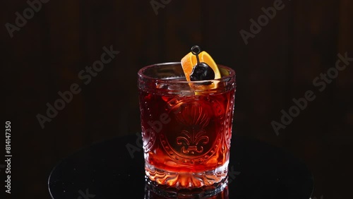 Perfect classic negroni cocktail in old fashioned faceted glass garnished with orange peel folded on metal skewer with olive. Alcoholic aperitif composed of gin, sweet vermouth and bitter.