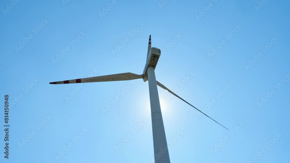 Timelapse windmill on a background of clear blue sky and sun. White blades of a wind turbine in close-up. A renewable energy source. Production of cheap and safe electricity. Timelapse windmill on a background of clear blue sky and sun. White blades of a wind turbine in close-up. A renewable energy source. Production of cheap and safe electricity.