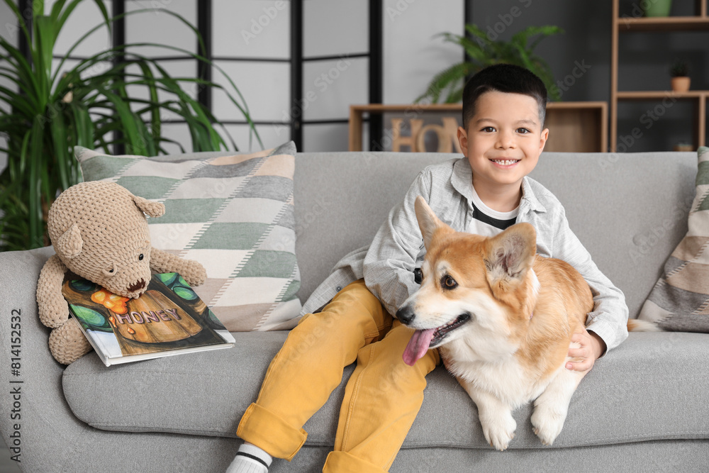 Little happy Asian boy with cute Corgi dog and book sitting on sofa at home Little happy Asian boy with cute Corgi dog and book sitting on sofa at home