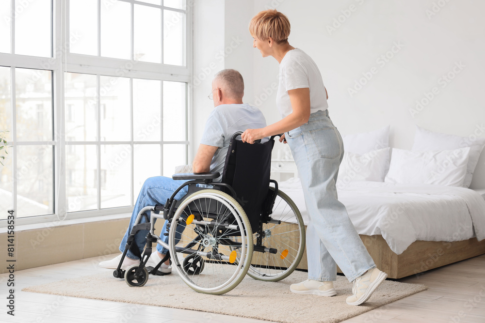 Mature woman with her sick husband in wheelchair at home Mature woman with her sick husband in wheelchair at home