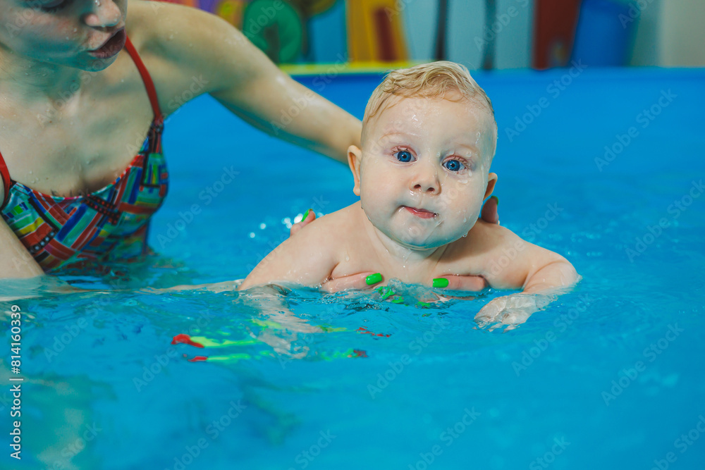 Swimming pool for babies. A little 8-month-old boy is learning to swim in the pool with a coach. Swimming pool for babies. A little 8-month-old boy is learning to swim in the pool with a coach.