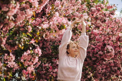 Meditative relaxed young woman surrounded pink spring blossoms. Concept of self-care mental health