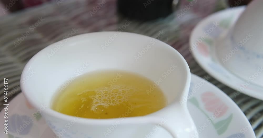 Pouring hot green tea from a thermos into a beautiful white cup Pouring liquid into cup on wooden table with drinkware Pouring hot green tea from a thermos into a beautiful white cup Pouring liquid into cup on wooden table with drinkware