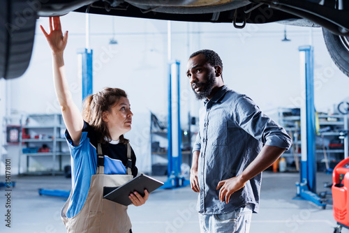 Slika na platnu African american client shocked by price after repairman in car service uses tablet to calculate repair invoice