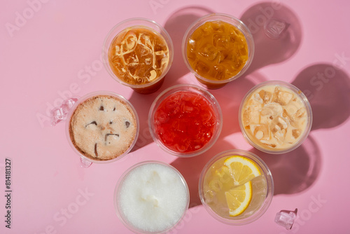 Colourful summer drinks with ice top view. Lemonades and coctails on pink background