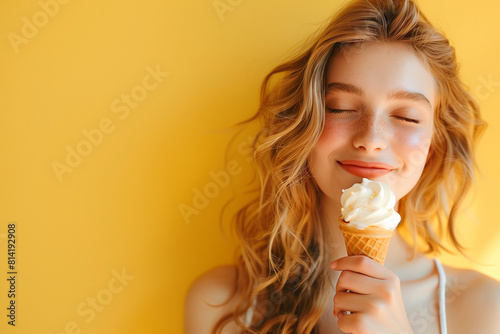A woman enjoys the icecream on the warm summer yellow background